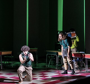 Teenage bully Rich Goranski (kneeling, played by Luke Surretsky) is the center of attention. Looking on is Jeremy Heere (played by Teddy Calvin) in Area Stage Company's 