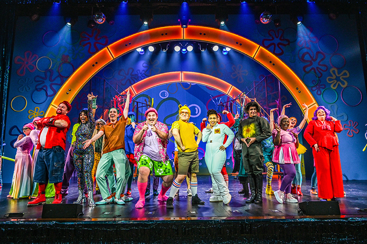 A large portion of Slow Burn's cast appear in their colorful costumes within the colorful set. (Photo by Larry Marano)